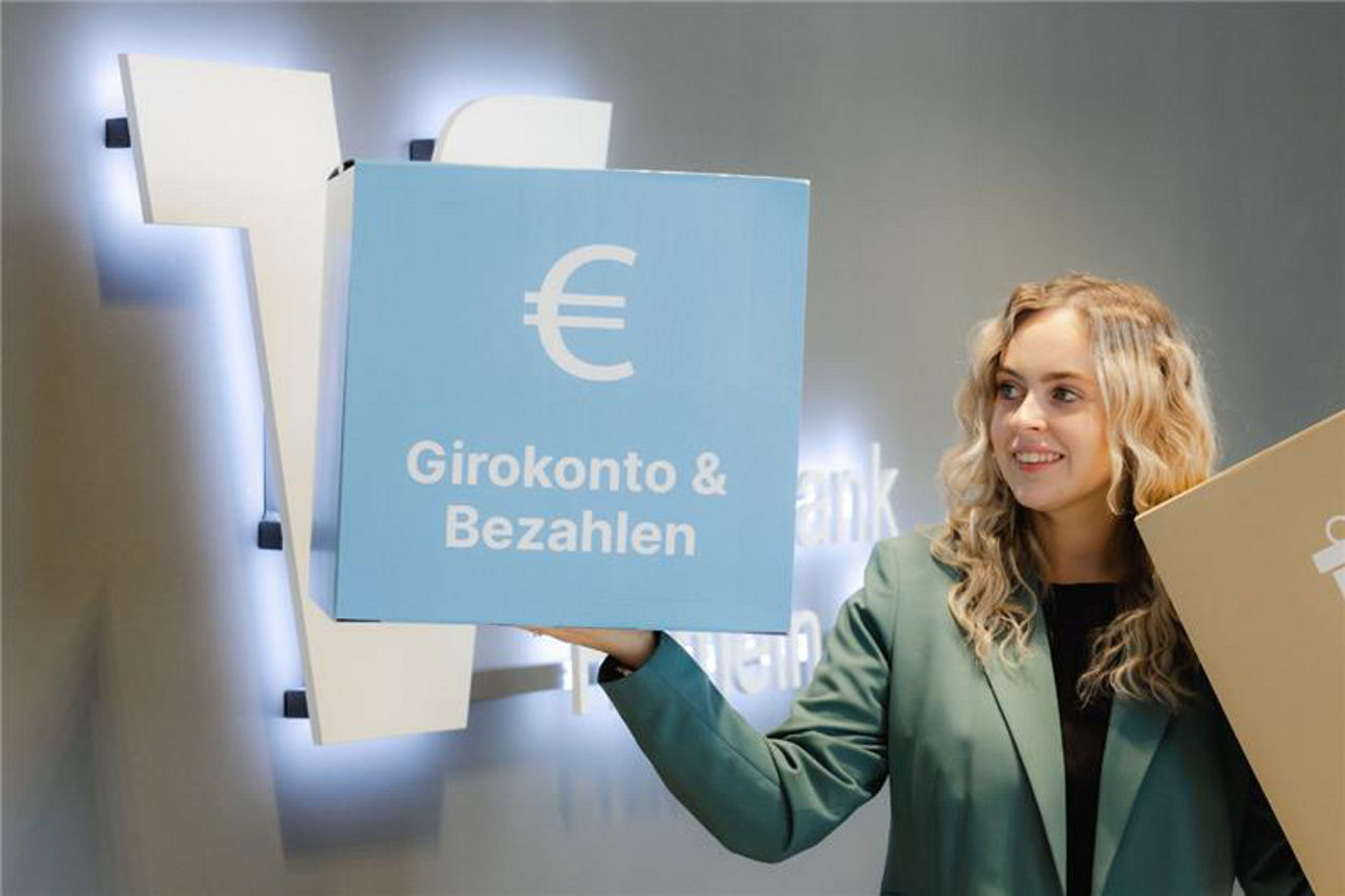 Eine Frau hält ein Schlid mit "Girokonto & Bezahlen" 