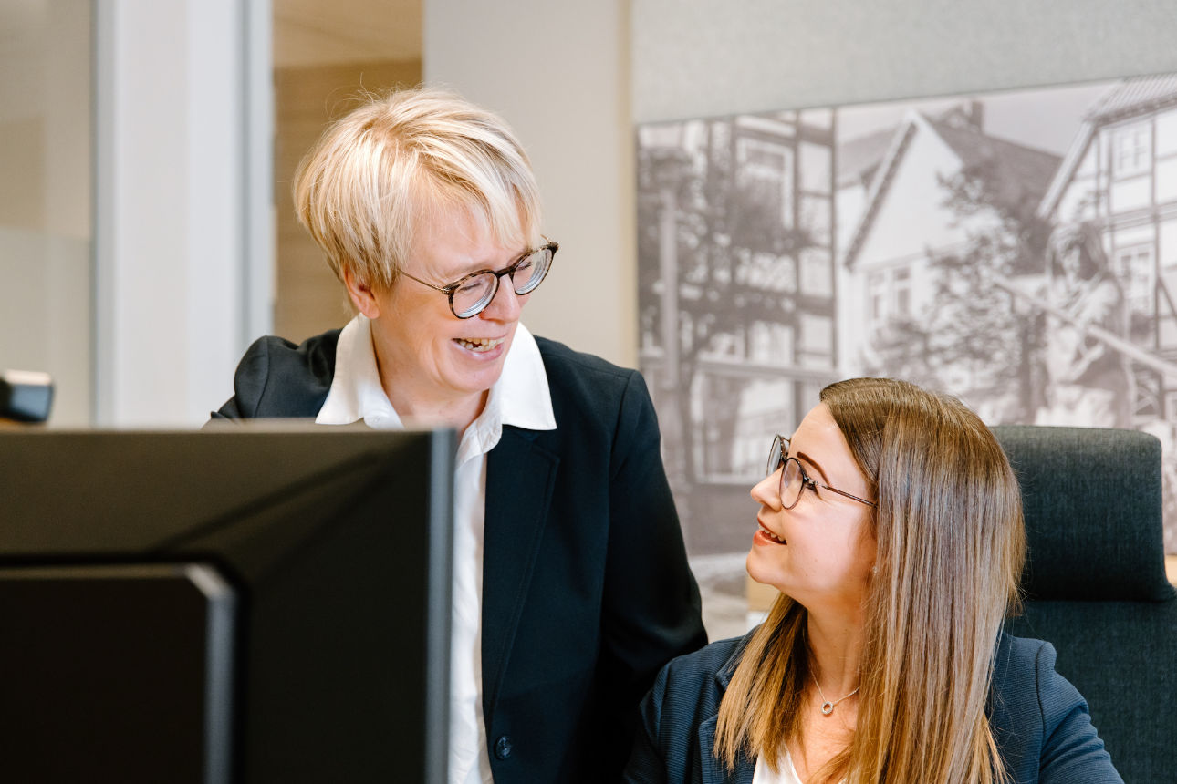 Zwei Personen in einem Büro, die gemeinsam auf einen Computerbildschirm schauen.