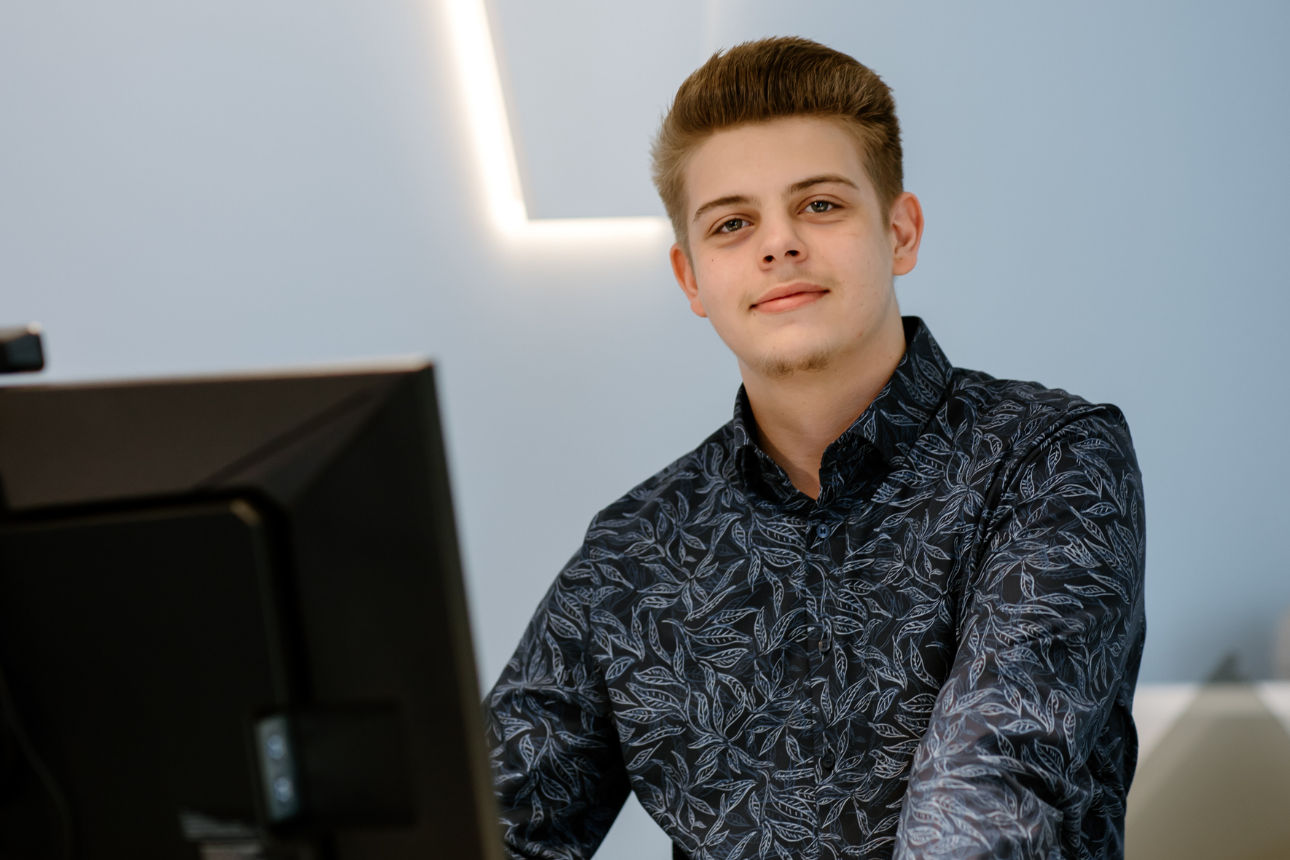 Eine Person in einem modern gestalteten Innenraum, die vor einem Computerbildschirm steht.