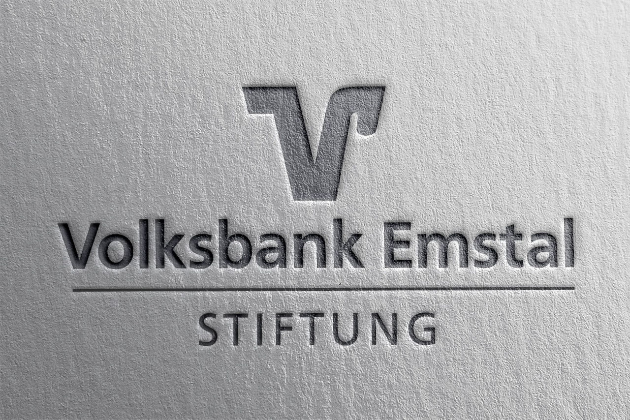 Drei Personen stehen lachend vor dem Schriftzug „Wir sind meine Bank.“