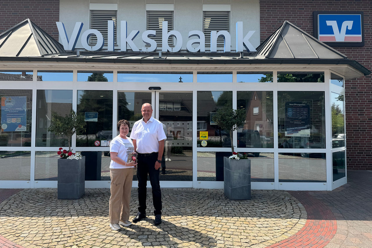 Jubiläum Hildegard Hinrichs: Ein Mann und eine Dame vor einer Volksbank Geschäftsstelle.