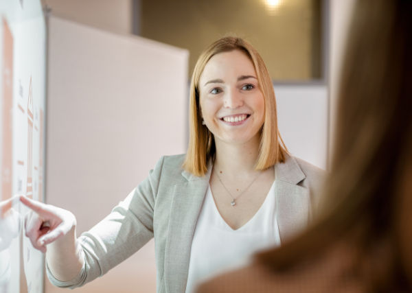 eine blonde Frau mit kurzen Haaren, die am Fenster lächelt