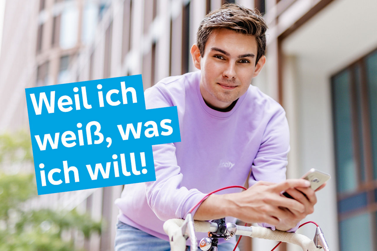 Junger Mann vor einem Business-Gebäude mit dem Claim in dem Bild Weil ich weiß, was ich will!