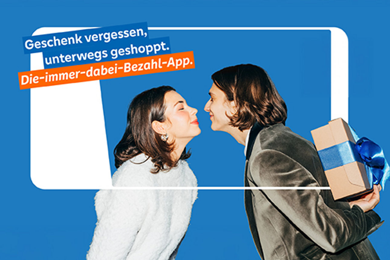 Frau und Mann kurz vor einem Kuss. Mann hält ein Geschenk hinter dem Rücken.