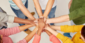 Mehrere Hände die sich in der Mitte übereinander legen, die ein Team symbolisieren 