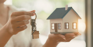Eine Person hält in den Händen ein Haus und die zugehörigen Schlüssel