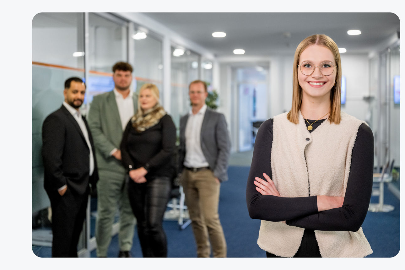 Eine Frau schaut in die Kamera und das Team steht hinter ihr.