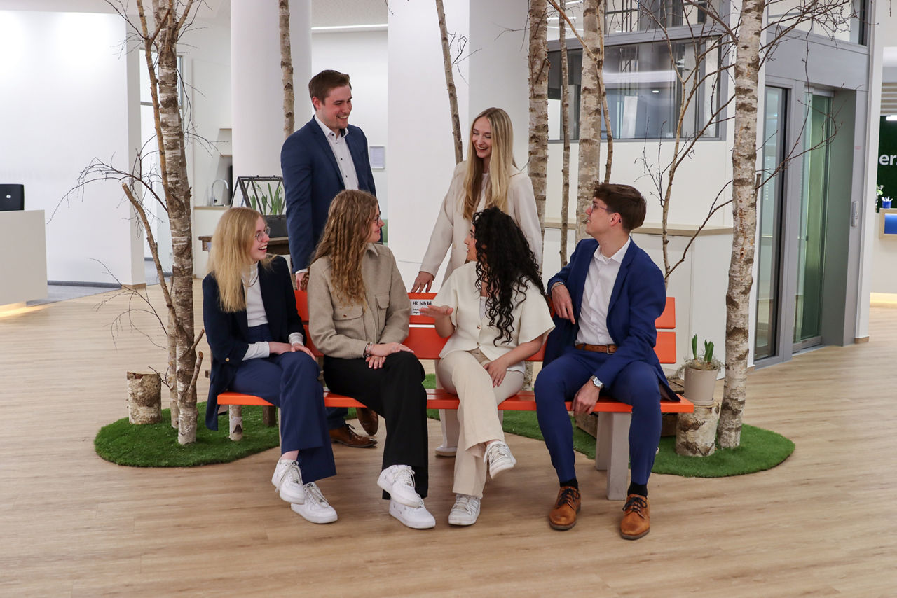 Eine Gruppe von jungen Bankmitarbeitern und Bankmitarbeiterinnen, die sich gegenseitig anschaut