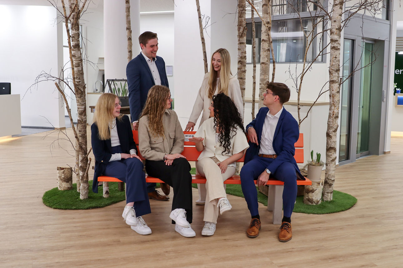 Eine Gruppe von jungen Bankmitarbeitern und Bankmitarbeiterinnen, die sich gegenseitig anschaut