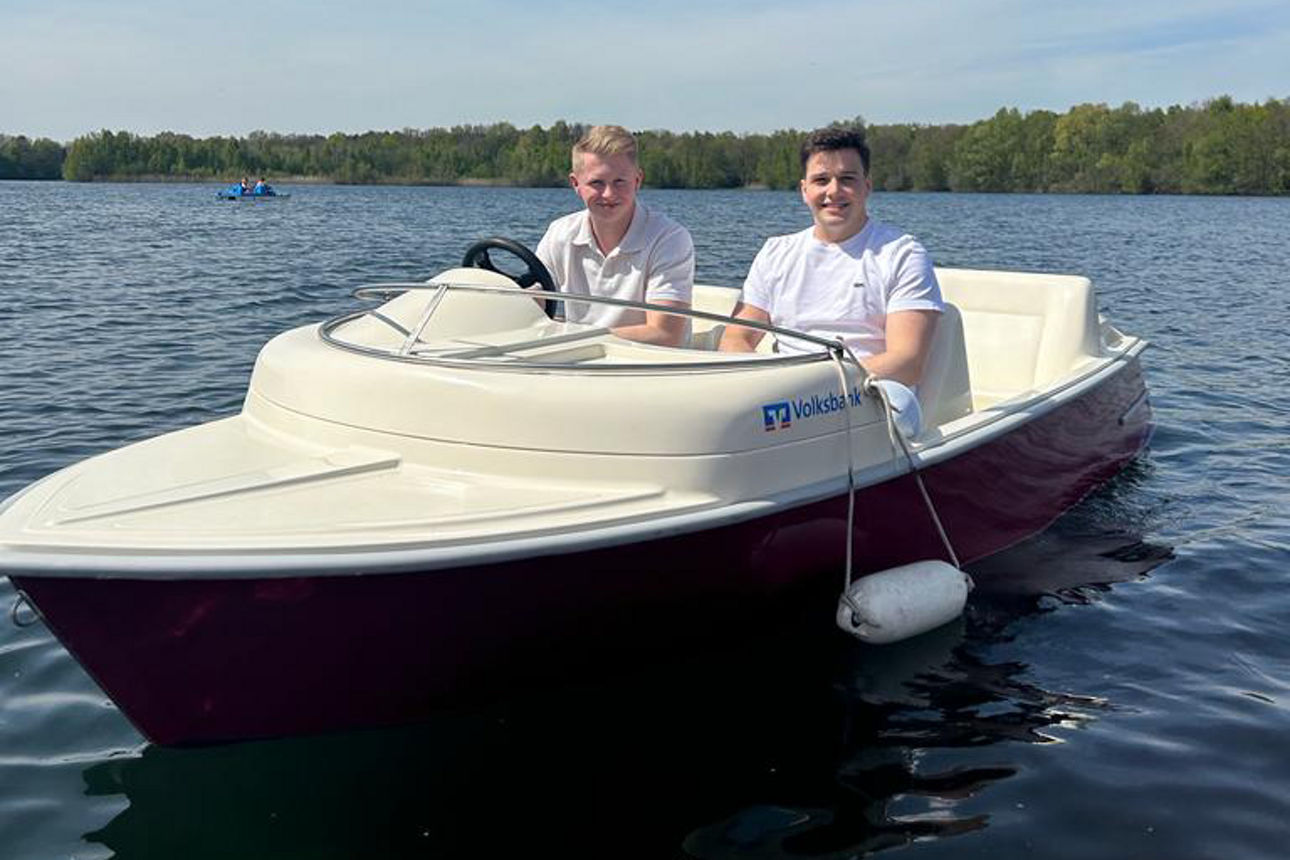 Zwei junge Männer fahren in einem kleinen Boot