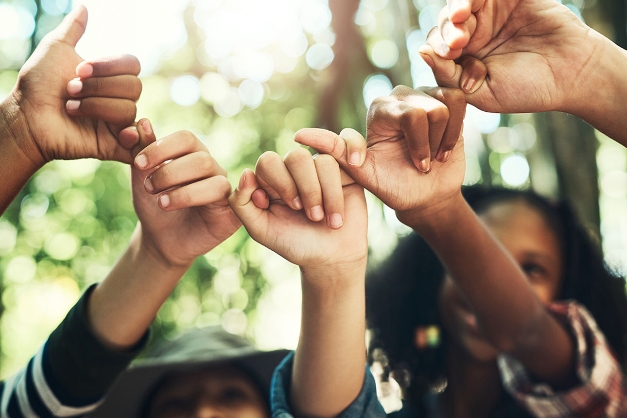 Gruppe von jungen Menschen die Ihre Hände zusammen in die Luft halten 