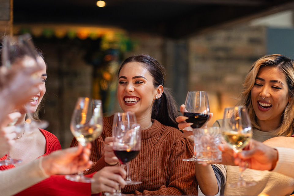 Drei Frauen unterschiedlicher Nationen stoßen mit Wein am Abend an