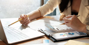 Eine Person sitzt am Schreibtisch vor einem Notebook
