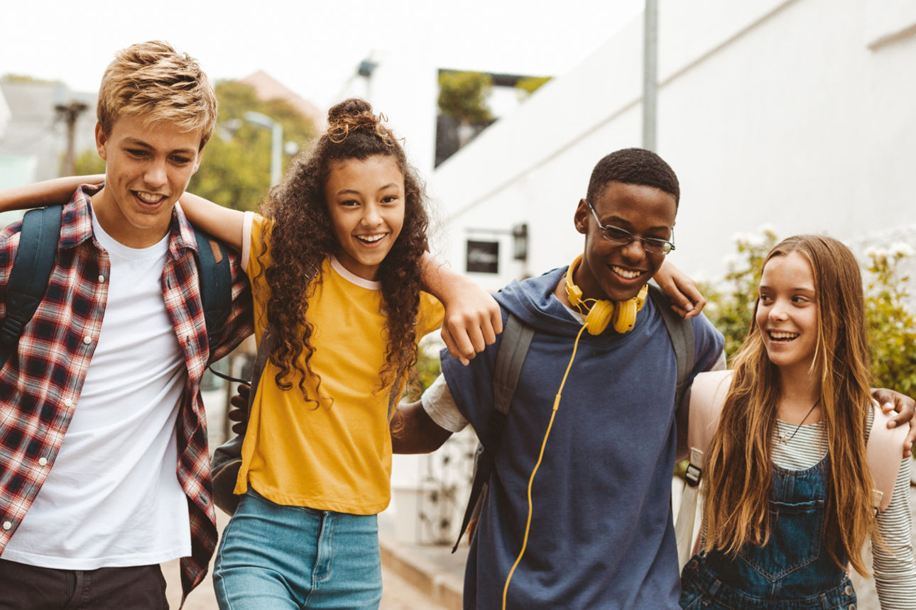 Gruppe aus Jugendlichen lächenlnd vor Gebäuden