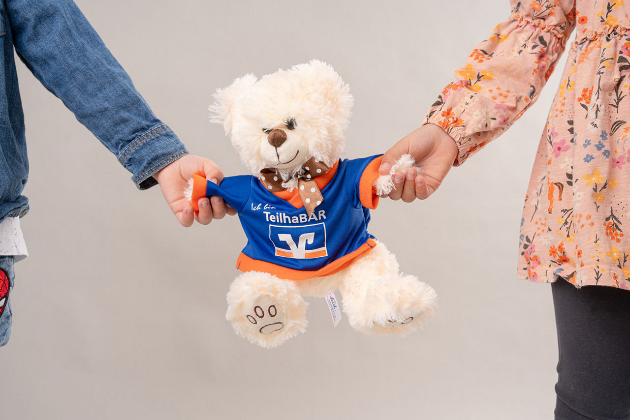 Zwei Kinder halten einen weißen Teddy