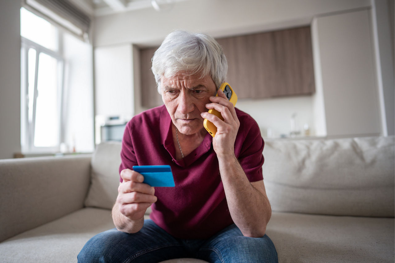 Mann am Telefonfon hält seine Bankkarte in der Hand