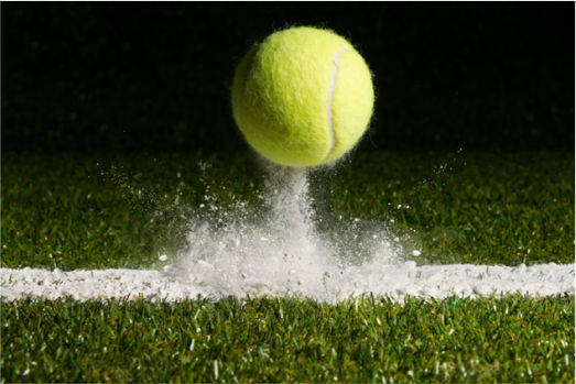 Ein Tennisball, der gerade auf dem Rasen aufschlägt.