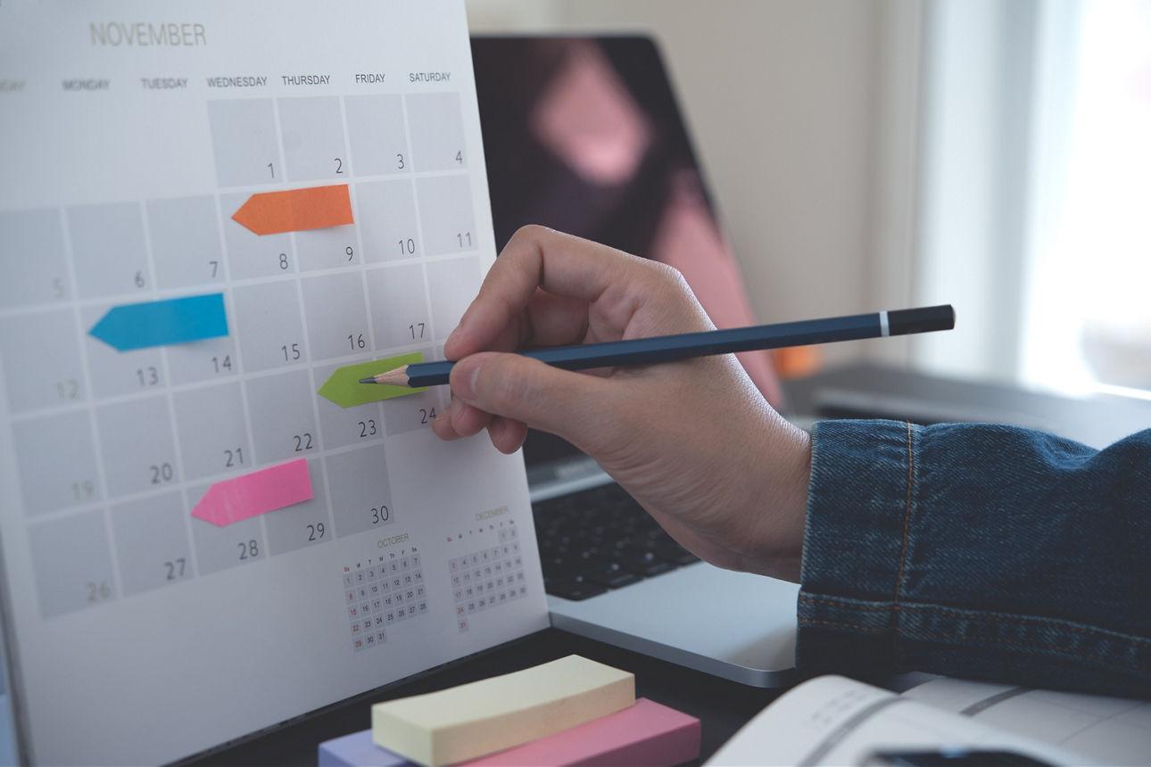 Ein Terminkalender, in den mit einem Bleistift ein Termin eingetragen wird.
