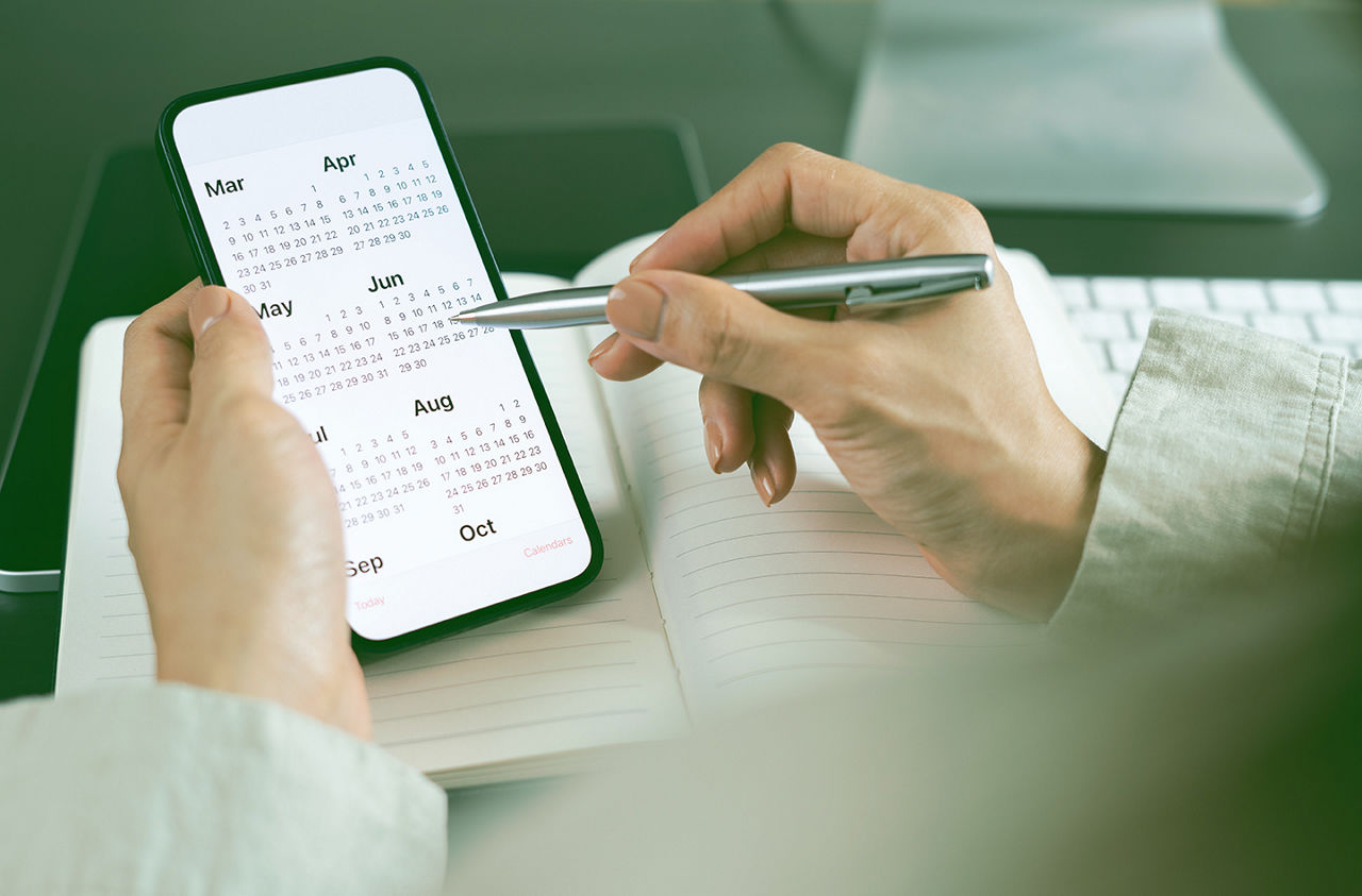 2026 Calendar event planner timetable agenda plan on organize schedule. Business woman using mobile phone with monthly calendar for event planning, Plan scheduling with laptop on office table