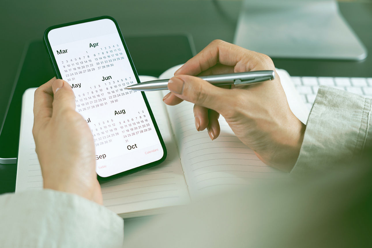 2026 Calendar event planner timetable agenda plan on organize schedule. Business woman using mobile phone with monthly calendar for event planning, Plan scheduling with laptop on office table