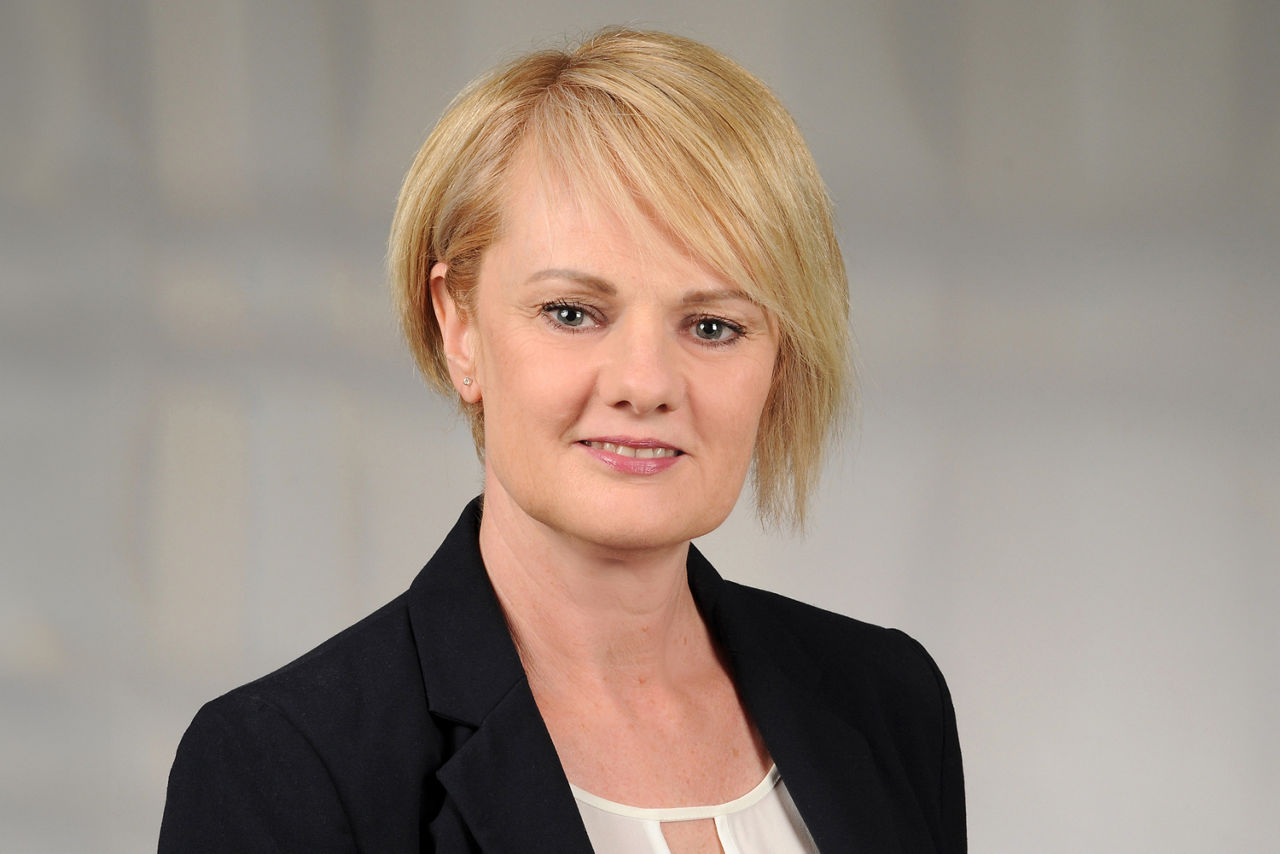 Heike Thielke-Alt hat kurze blonde Haare mit einem Schrägpony und trägt ein Businessoutfit