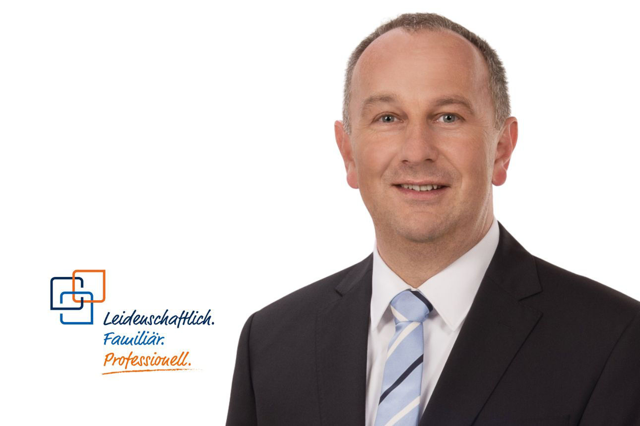Porträt von Thomas Klaar, einem lächelnden Mann mit grauen Haaren im dunklen Anzug mit hellblau gestreifter Krawatte. Daneben das Firmenlogo und der Slogan "Leidenschaftlich. Familiär. Professionell."