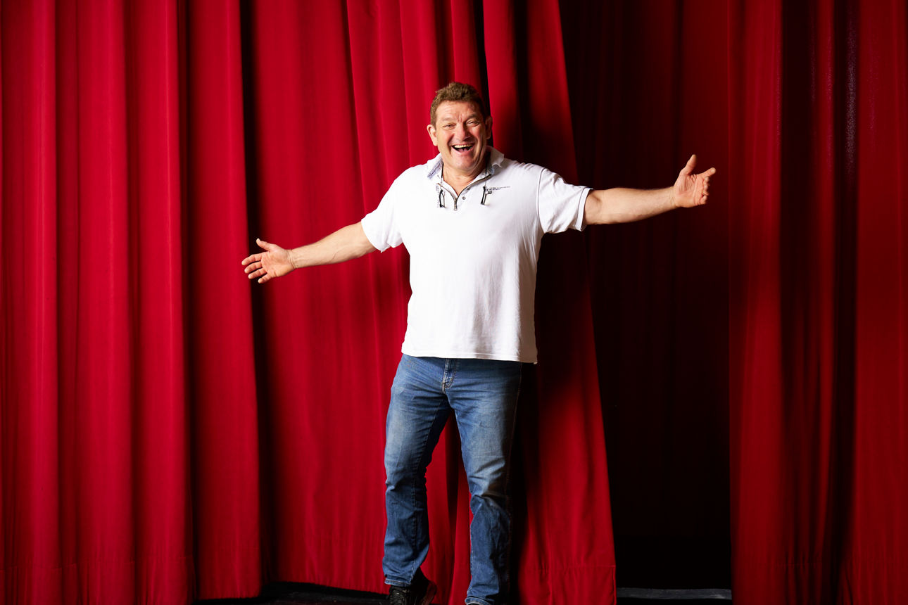 Thomas Boxhammer steht vor einem roten Vorhang