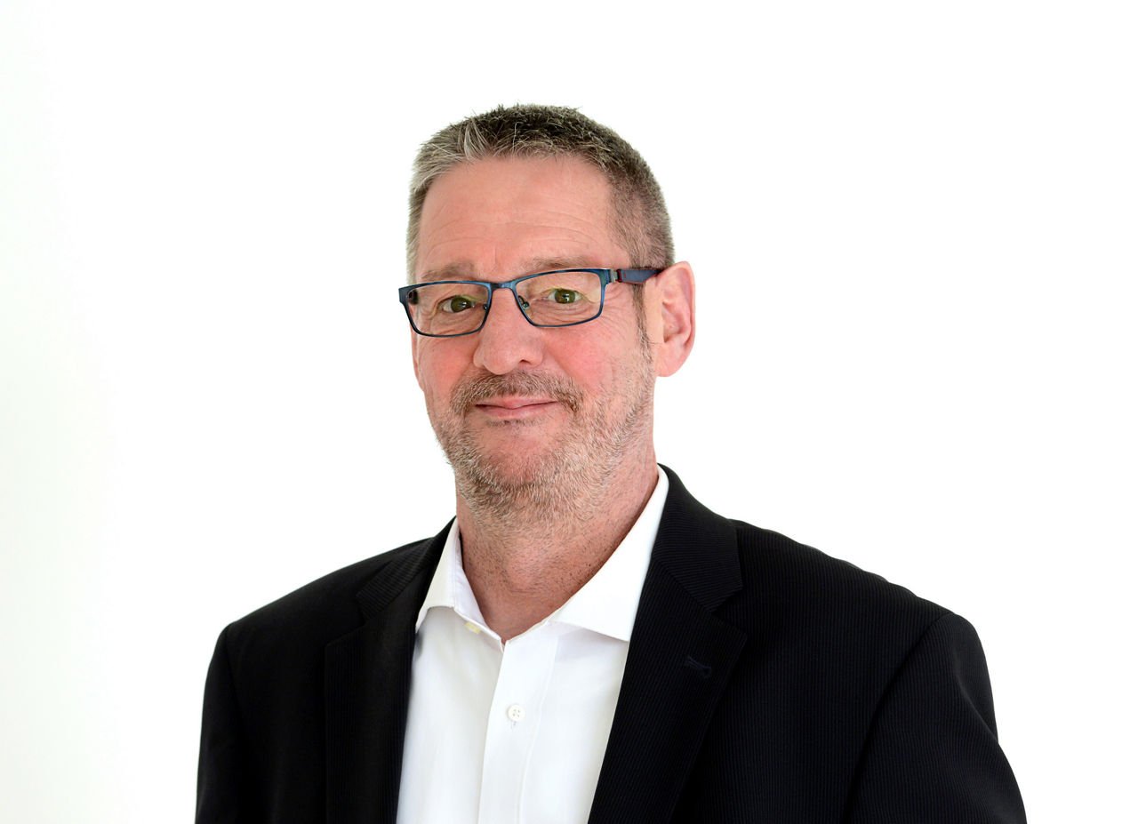 Firmenkundenberater Thomas Köster vor grauen Hintergrund