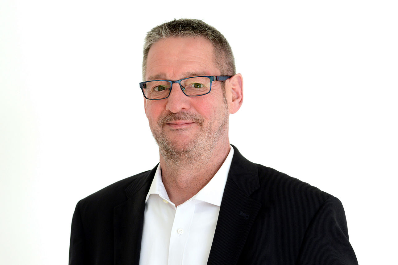 Firmenkundenberater Thomas Köster vor grauen Hintergrund