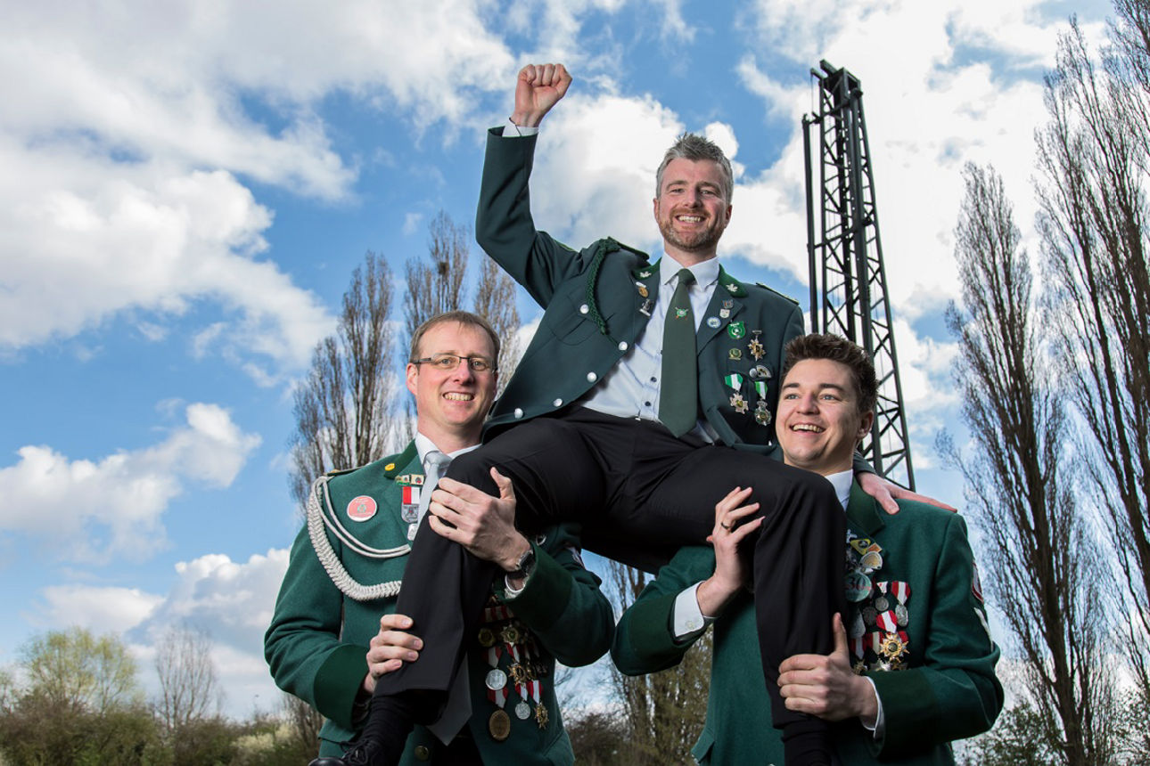 Zwei Männer in Schützenuniform halten einen dritten Schützen auf den Schultern