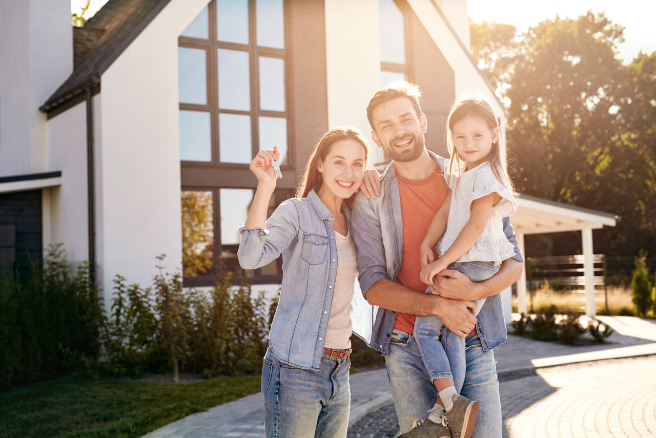 Eine junge Familie steht vor einen Haus