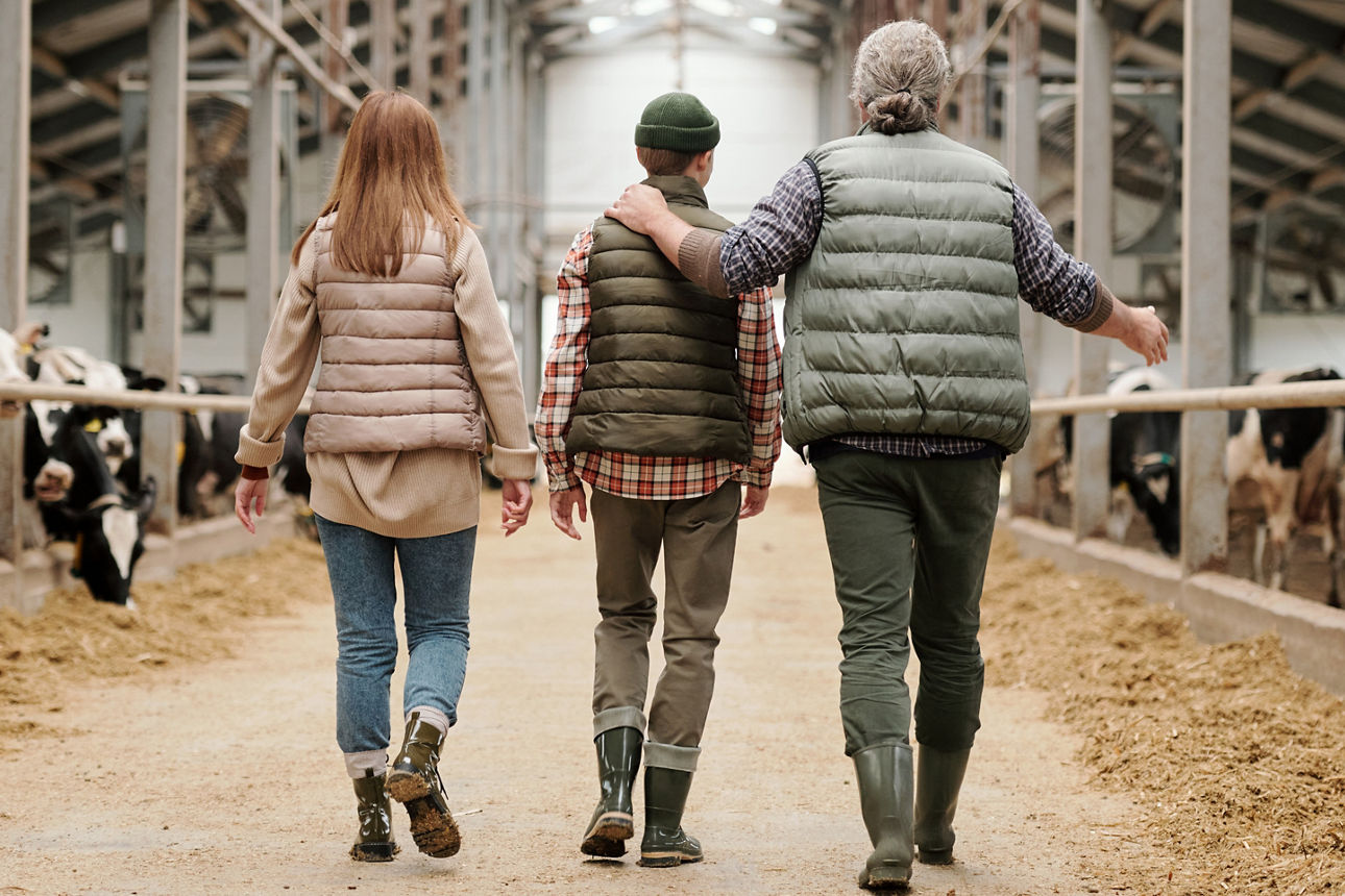 Ein Landwirt geht mit seinen Kindern durch den Kuhstall