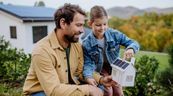 Eine Mann und ein Kind schauen zusammen auf ein Papphaus