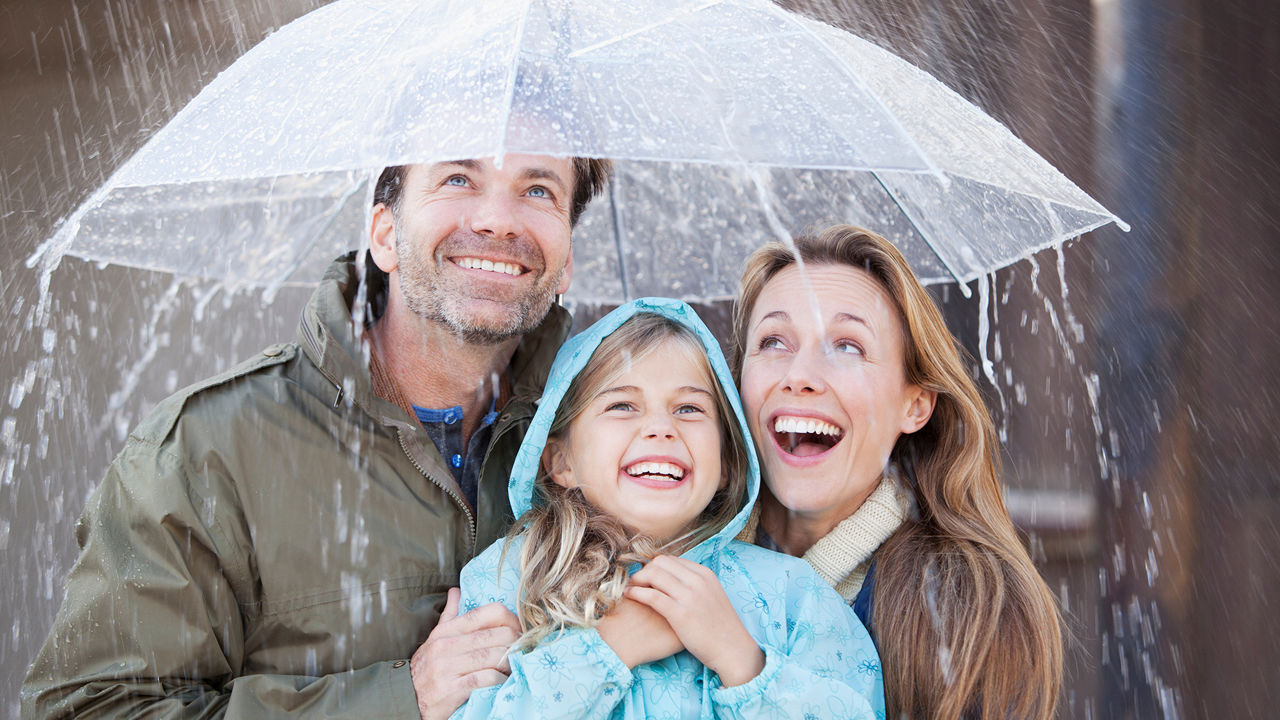 Familie steht im Regen unter einem Regenschirm
