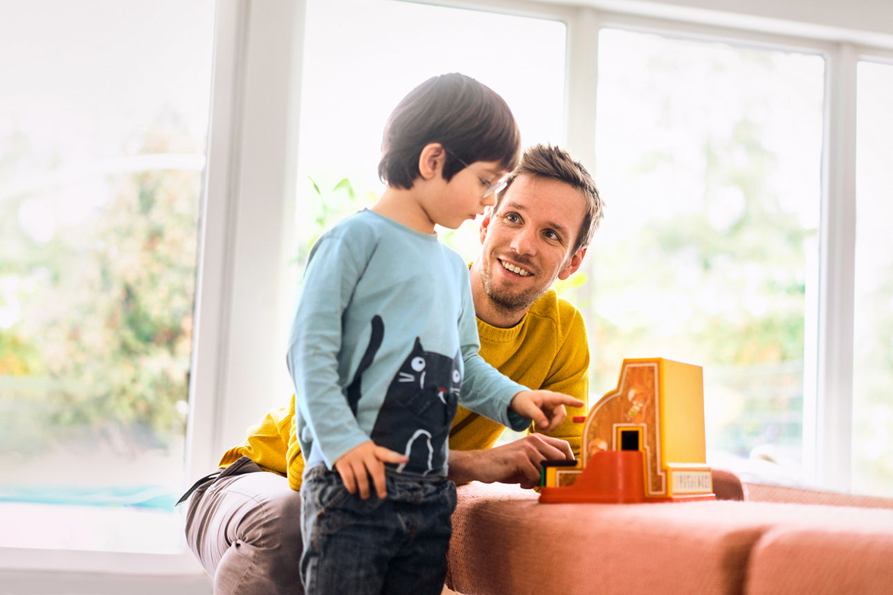 Mann mit Kind beim spielen im Wohnzimmer