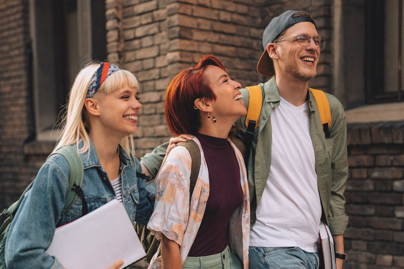 3 Jugendliche laufen nebeneinander und lachen