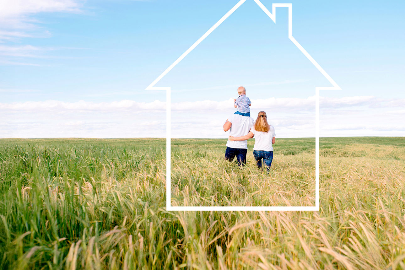 Familie steht in einer Graslandschaft und wird von einem Rahmen in Haus-Form umfasst