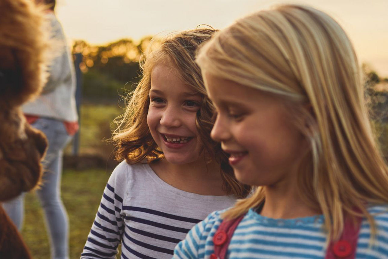 Zwei Mädchen streicheln ein Alpaka