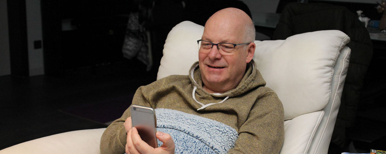Mann liegt auf Sofa und schaut in sein Smartpone