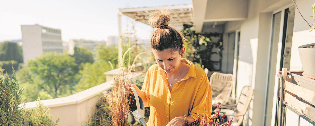 Eine Frau giesst die Pflanzen auf ihrem Balkon
