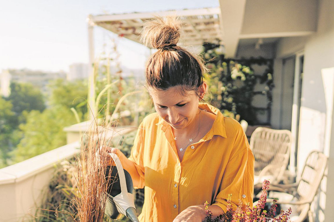 Eine Frau giesst die Pflanzen auf ihrem Balkon