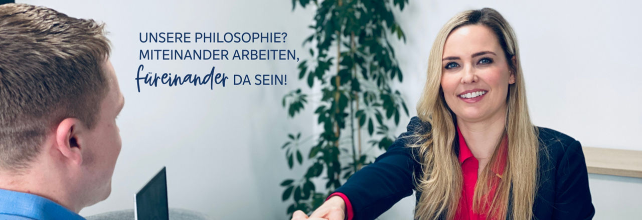 Ein junge Frau sitzt lächelnd am Schreibtisch