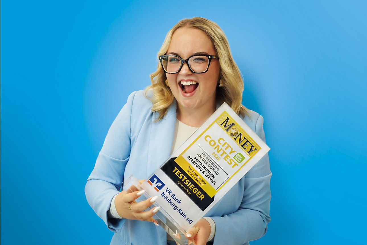 Junge Mitarbeiterin mit Brille hält lachend ein "Testsieger" Siegel in den Händen