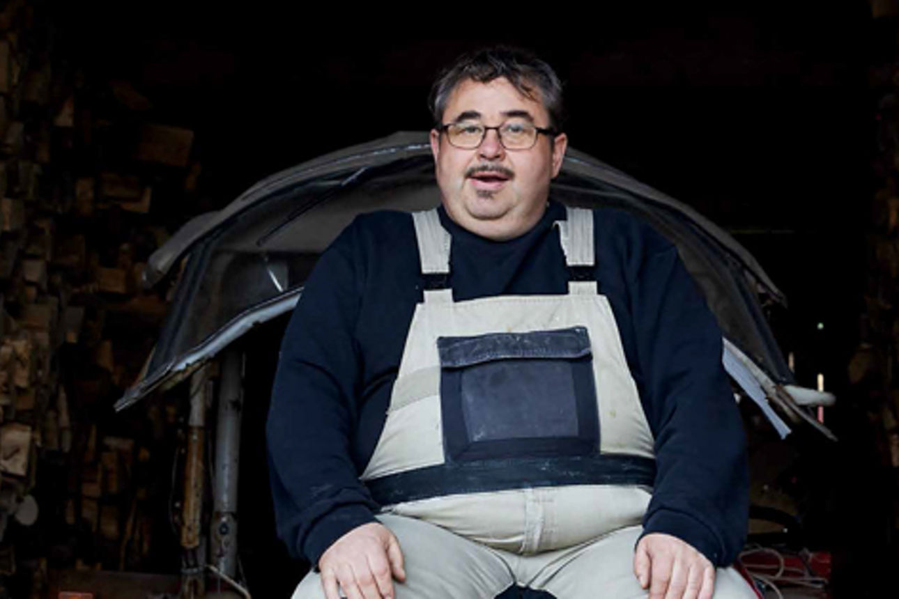 Ein Mann sitzt auf einem Traktor in einer Scheune voller Holz