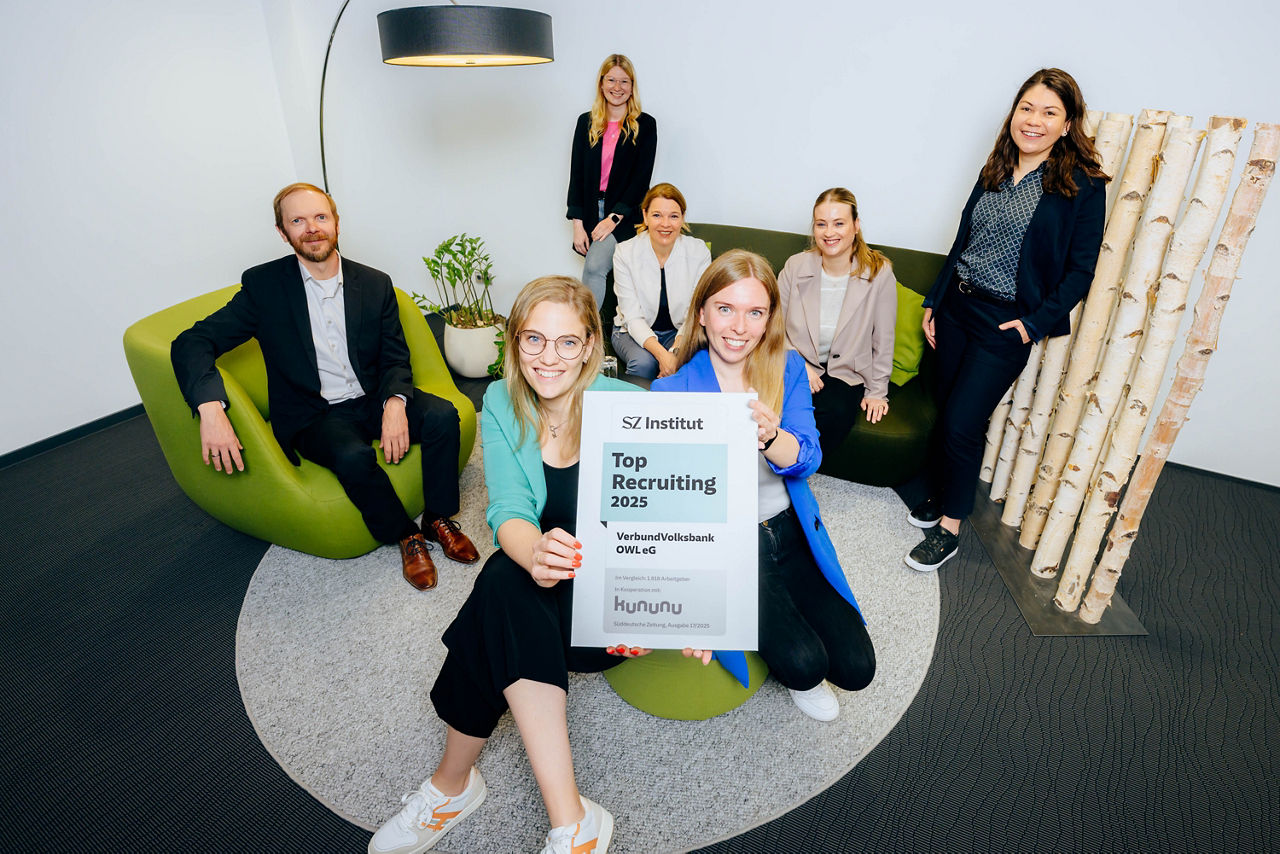 Das Team Personalmanagement der VerbundVolksbank OWL freut sich über die Auszeichnung und hält das Siegel in die Kamera. 