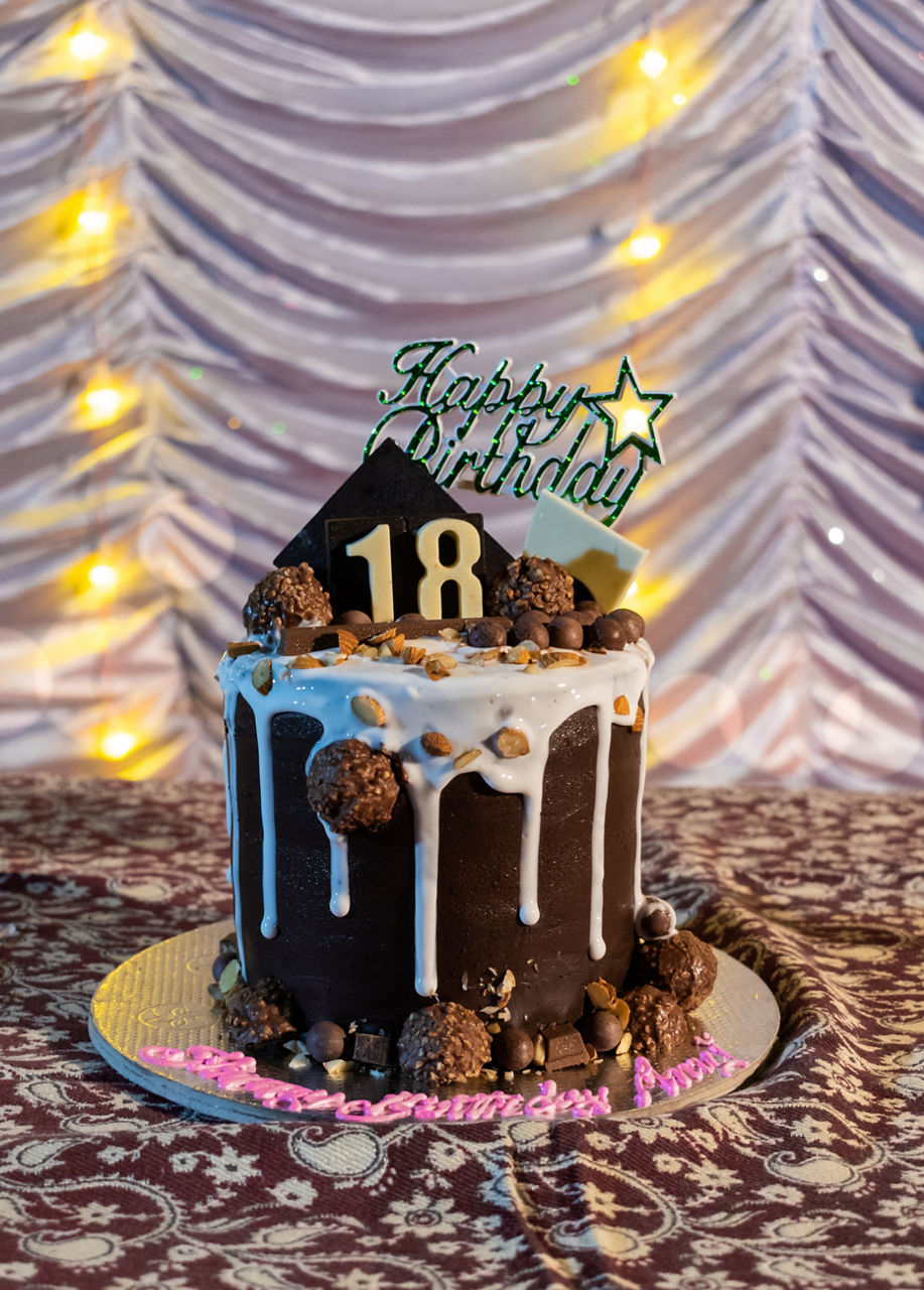 Dunkle Schokoladentorte mit „Happy Birthday“ und der Zahl 18, dekoriert mit Süßigkeiten.
