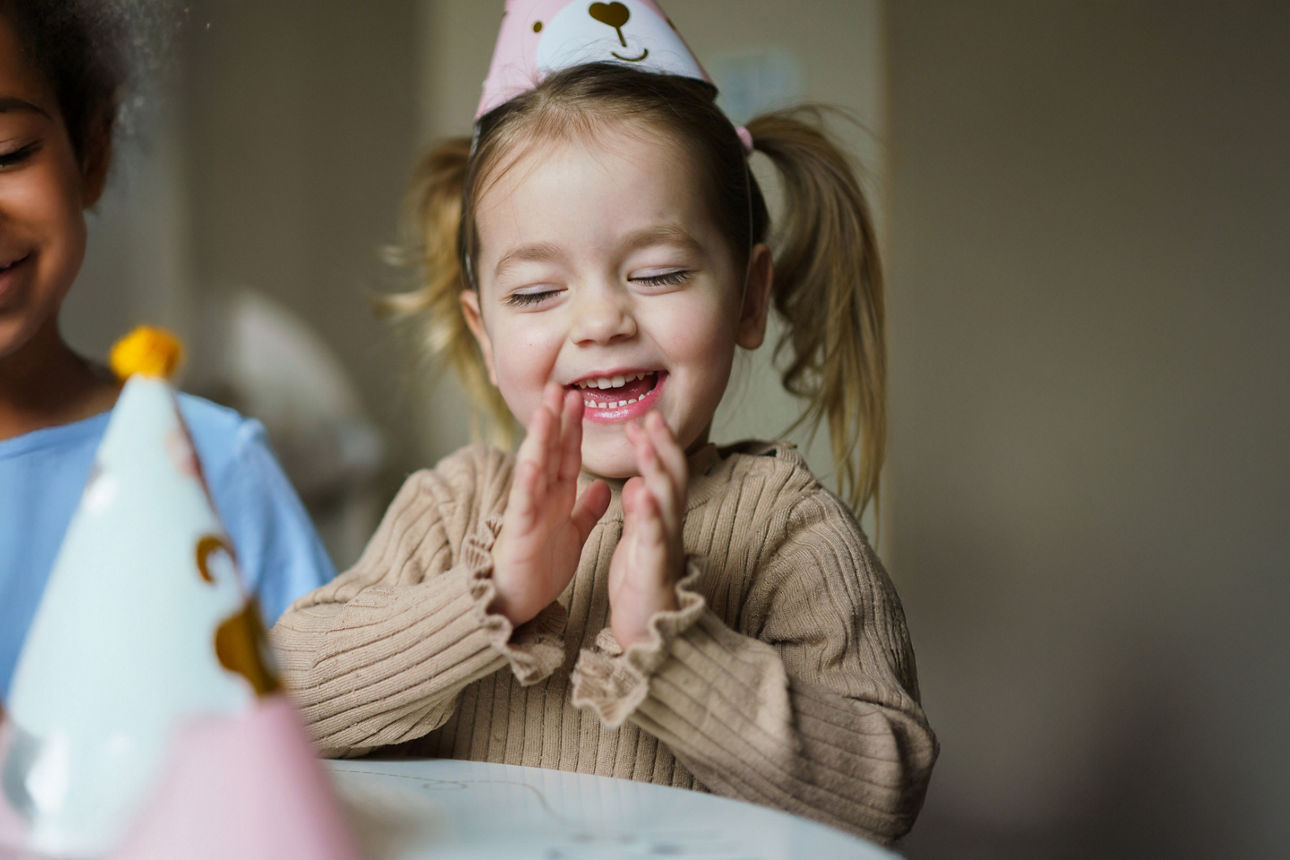 Kind klatscht in die Hände, trägt Partyhut; Logos von Union Investment und VR Bank sichtbar.