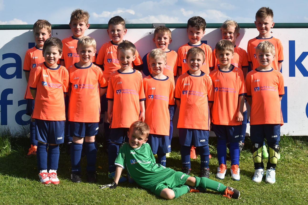 Bild von einem Kinderfußballteam in orangenen Trikots.