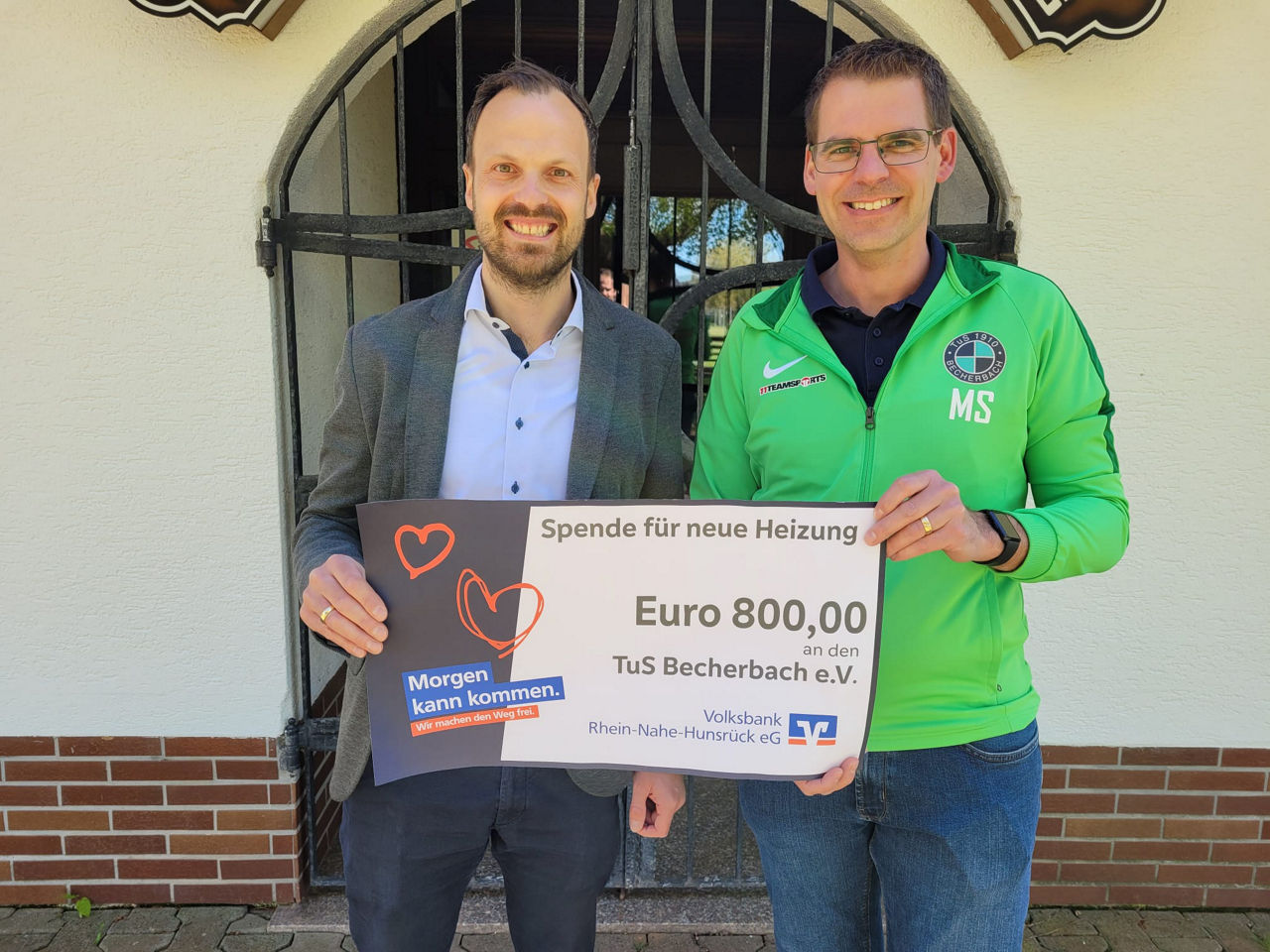 Zwei Erwachsene halten einen Spendenscheck in der Hand.