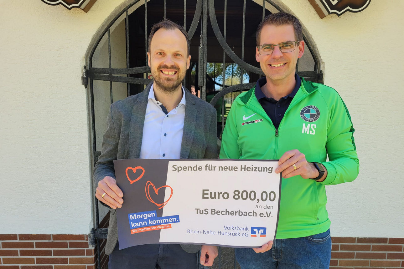 Zwei Erwachsene halten einen Spendenscheck in der Hand. 